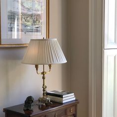 a lamp sitting on top of a wooden table next to a framed picture and books