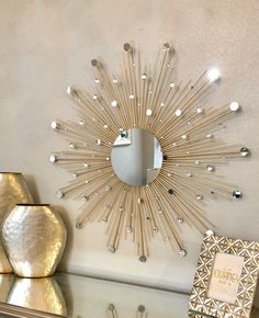 a sunburst shaped mirror hanging on the wall above a table with other items