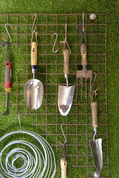 gardening utensils are laid out on a metal grate in the grass with wire fencing around them