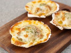 three small shells with cheese and herbs in them on a cutting board, ready to be eaten