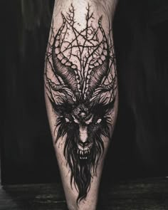 a black and white photo of a demon with horns on his leg, done in ink