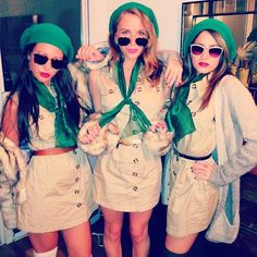 three women dressed in green hats and scarves posing for the camera with their arms around each other