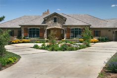 a large house with lots of plants and flowers around it's front entrance area