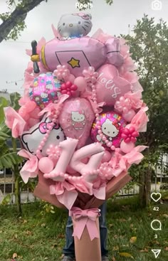 a bunch of hello kitty balloons in a pink bouquet on top of a grass field