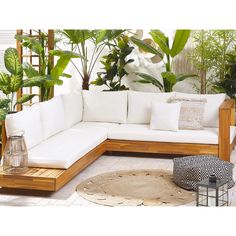 a large white couch sitting on top of a wooden floor next to potted plants