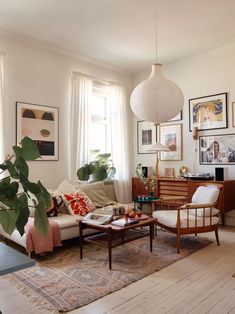 a living room filled with lots of furniture and pictures on the wall next to a window