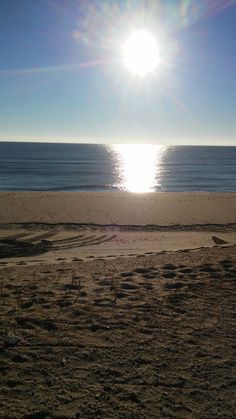 the sun is shining over the water on the beach near the sand and sea shore