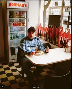 a man sitting at a table in front of a refrigerator