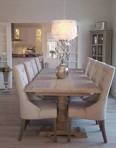 a dining room table with white chairs and a chandelier hanging from the ceiling