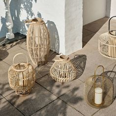 four wicker lanterns sitting on the ground next to a white building with shadows cast onto it