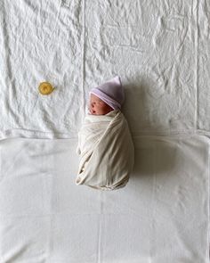 a baby wrapped up in a blanket on top of a bed next to a button