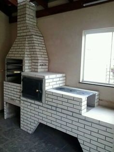 a white brick oven sitting in the middle of a room next to an open window