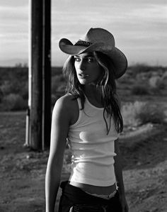 a woman wearing a cowboy hat standing next to a pole