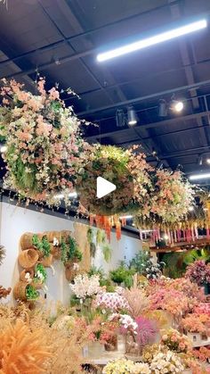 a flower shop filled with lots of different types of flowers and hanging baskets on the ceiling