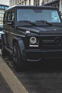 a black mercedes g - class is parked on the street