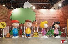 a group of cartoon figures standing in front of a brick wall with a sign that says bus stop