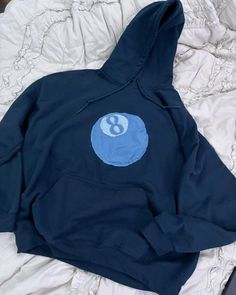 a blue hoodie with the number eight on it sitting on top of a bed