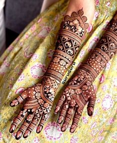 two hands with henna tattoos on them, one is showing off the intricate design