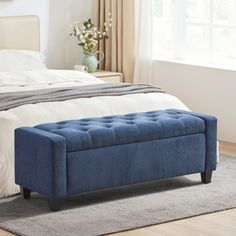 a blue bench sitting on top of a bed in a bedroom next to a window