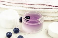 a jar of blueberries sits next to a pile of white towels and soaps