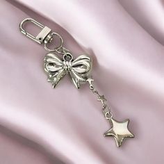 a metal keychain with a bow and star charm on it's side