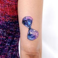 a woman's arm with a tattoo on it that has an hourglass in the middle