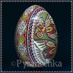 an ornate painted egg on a stand against a black background