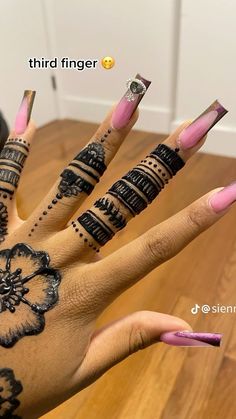 a woman's hand with tattoos on it and pink nail polishes in the middle