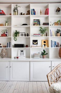 a living room filled with lots of white bookshelves covered in plants and potted plants