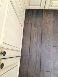 a kitchen with white cabinets and wood floors