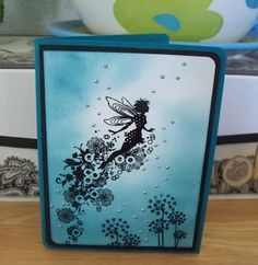 a card with a tinkerbell fairy on it sitting on a table next to a potted plant