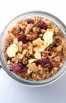 a glass bowl filled with granola and cranberries