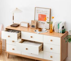 a white dresser with drawers and a lamp next to it on top of a hard wood floor