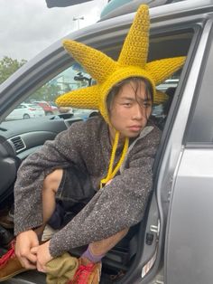 a man sitting in the back seat of a car wearing a yellow knitted hat