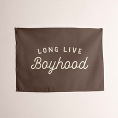 a flag with the words long live boyhood on it hanging from a white wall