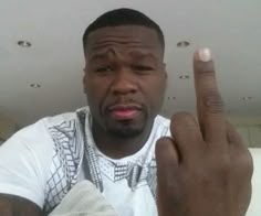 a close up of a person giving the peace sign with his hand and wearing a white t - shirt