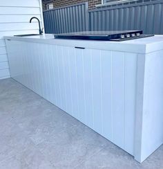 an outdoor kitchen with a sink and faucet on the side of the house