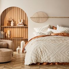 a large bed sitting next to a chair and book shelf on top of a hard wood floor