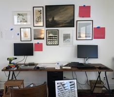 a desk with several computer monitors and pictures on the wall