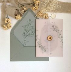 three different colored envelopes on top of each other next to some dried flowers and burlap