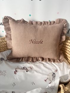 a pink pillow sitting on top of a wicker chair next to a white wall