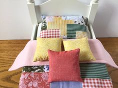 a bed topped with lots of pillows on top of a wooden floor