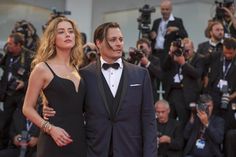 a man and woman standing next to each other in front of photographers on the red carpet