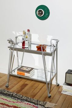 a glass table with metal legs and a green lamp above it on top of a wooden floor