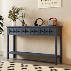 a blue console table with two drawers on each side and a potted plant next to it