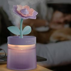 a purple vase with a flower in it sitting on a table