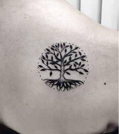 a black and white tree tattoo on the back of a woman's upper body