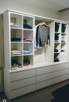 a white closet with clothes and shoes on it's shelves, next to a window