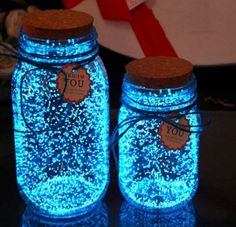 two mason jars with tags on them are lit up in blue and brown glitters