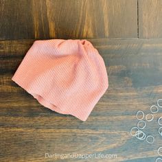 a pair of scissors and some wire on a wooden table next to a pink shirt